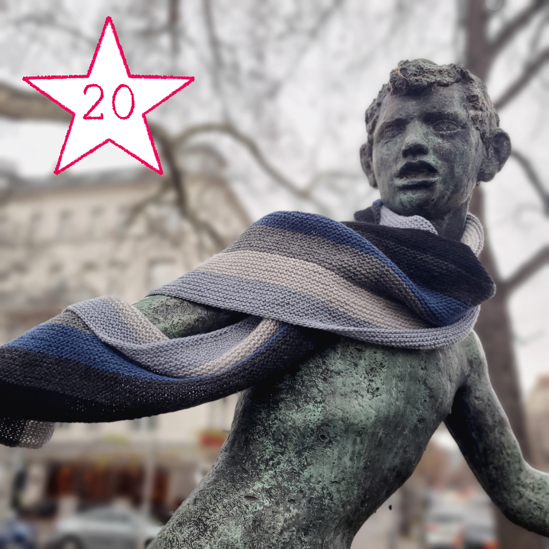 Knabenstatue trägt längsgestreiften Schal in Grau- und Blautönen